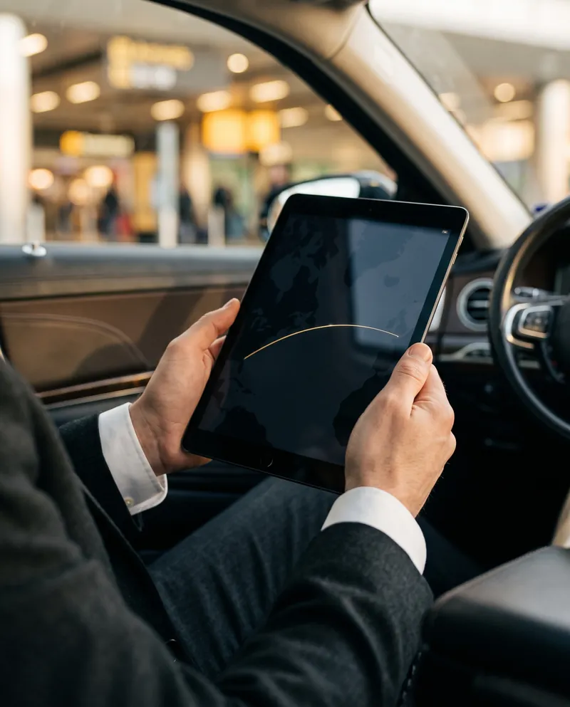 Chauffeur checking a flight on a tablet in the arrivals hall